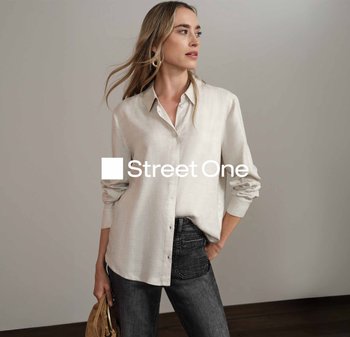 Chemise boutonnée gris clair à manches longues et coupe décontractée, associée à un jean noir. Tissu texturé avec un design simple.