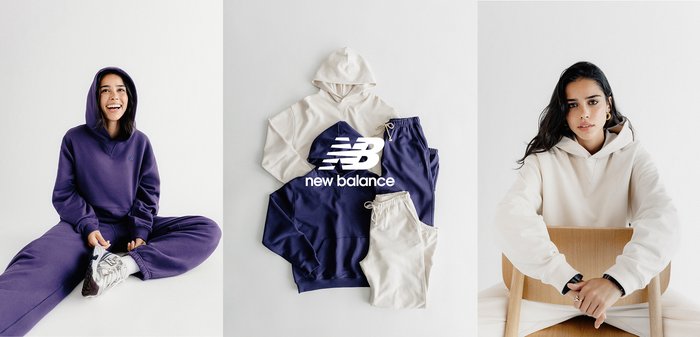 Dos mujeres con sudaderas con capucha y pantalones deportivos en tonos morado y crema; logotipo de New Balance con ropa a juego en colores crema y azul marino dispuesta sobre una superficie plana.