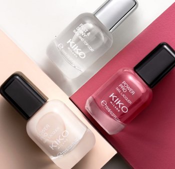 Three nail polish bottles displayed: a clear topcoat, a creamy white, and a vibrant pink, all with KIKO branding and black caps.