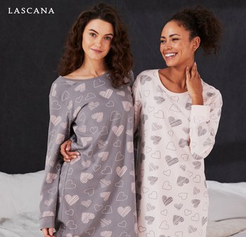 Kaksi naista rentoihin yöpukuihin pukeutuneina: toinen harmaa valkoisin sydänkuvioin, toinen vaaleanpunainen vastaavin kuvioin. Pehmeä kangas, pitkät hihat.