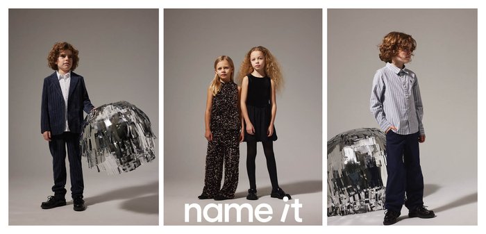 Quattro bambini in abiti festivi; due ragazzi in giacca si trovano vicino a sfere di dischi argentate, e due ragazze posano in abiti neri e di paillettes su sfondi semplici.