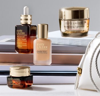Estée Lauderin ihonhoito- ja meikkituotteet pinotun kirjapinon päällä, mukana Advanced Night Repair- ja Double Wear -meikkivoiteen pullot.