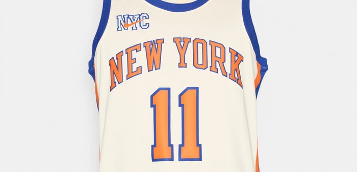 Μπλουζάκι μπάσκετ σε κρεμ απόχρωση με μπλε και πορτοκαλί λεπτομέρειες. Φέρει τα λόγια "NEW YORK" και τον αριθμό "11" τυπωμένα με έντονα γράμματα, με μπλε γιακά.