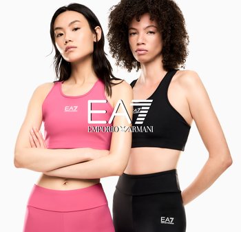 Dwie kobiety w stroju sportowym, jedna w różowym staniku sportowym i legginsach, druga w czarnym staniku sportowym i legginsach, patrzące przed siebie z pewnością siebie.