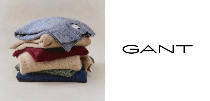 Stapel von fünf Pullovern in Blau, Beige, Maronenrot, Grün und Blau mit verschiedenen Strick- und Zopfmuster; Etikett auf dem obersten Pullover sichtbar.