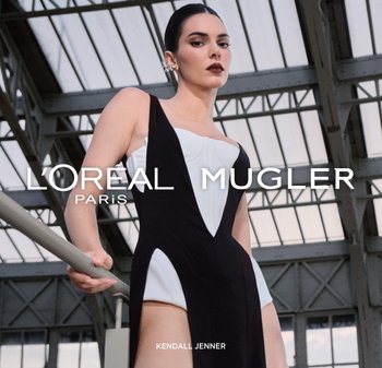 Schwarzes und weißes eng anliegendes Kleid mit geometrischem Design, mit tiefem Ausschnitt und seitlichen Ausschnitten, kombiniert mit silbernen Ohrringen.