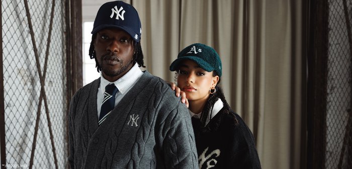 To personer har hatte på: den ene bærer en marineblå kasket med et hvidt logo og en grå kabelstrikket sweater; den anden en grøn tekstureret kasket og en sort sweater.