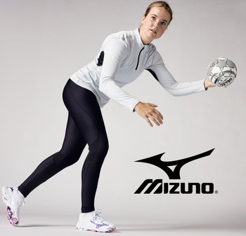 Conjunto deportivo que incluye una camiseta blanca de manga larga con cremallera parcial y mallas negras. Las zapatillas son blancas con acentos coloridos. Sosteniendo un balón de mano.