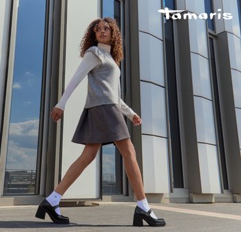 Model in a light grey knitted sleeveless top, dark flared skirt, and chunky black platform heels, paired with white ankle socks.
