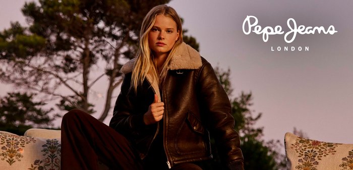 Giubbotto aviatore in pelle marrone con colletto in shearling crema, dotato di chiusura con zip e tasche laterali. Ambientato su uno sfondo naturale.