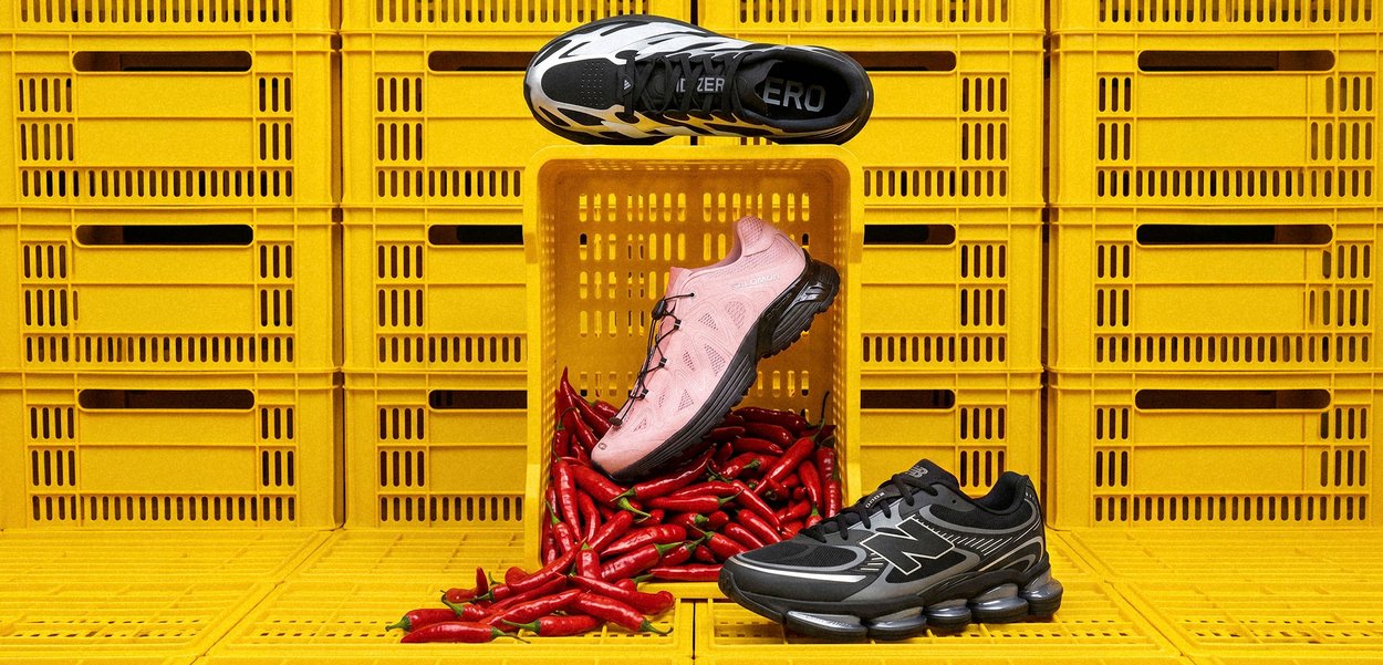 Scarpe da corsa nere e bianche, rosa e nere esposte con peperoncini rossi su uno sfondo di cassetta gialla.