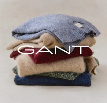 Stapeltje van zes gebreide truien in verschillende kleuren: blauw, beige, rood, groen en marineblauw. Kenmerken zijn texturen en patronen. Merknnaam "GANT" prominent weergegeven.