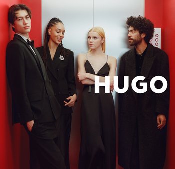 Vier figuren in formele kleding staan in een lift. Ze dragen zwarte pakken en een elegante zwarte jurk. De achtergrond is rood met een liftpaneel.