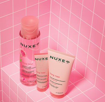 Prodotti per la cura della pelle NUXE Very Rose: una bottiglia di acqua micellare rosa trasparente, un tubo di scrub rosa con un tappo testurizzato e un tubo di gel detergente rosa.