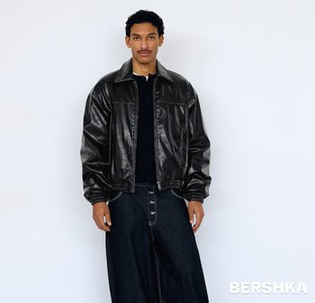 Černá kožená bomber bunda se zipem vpředu, žebrovanými manžetami a pasem. Nošená přes černé tričko a doplněná tmavým denimem.