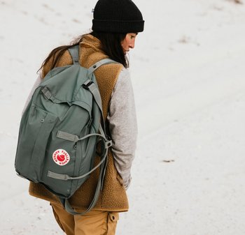 Olivgrüner Rucksack aus strapazierfähigem Stoff, ausgestattet mit mehreren Taschen, verstellbaren Trägern und einem runden Logopatch auf der Vorderseite.
