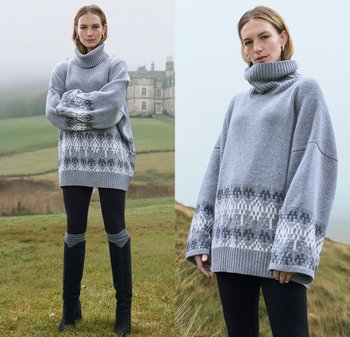 Grauer, übergroßer Pullover mit hohem Rollkragen, aufwendigem Muster in dunklerem Grau und Weiß am Saum, getragen mit schwarzen Leggings und kniehohen Stiefeln.