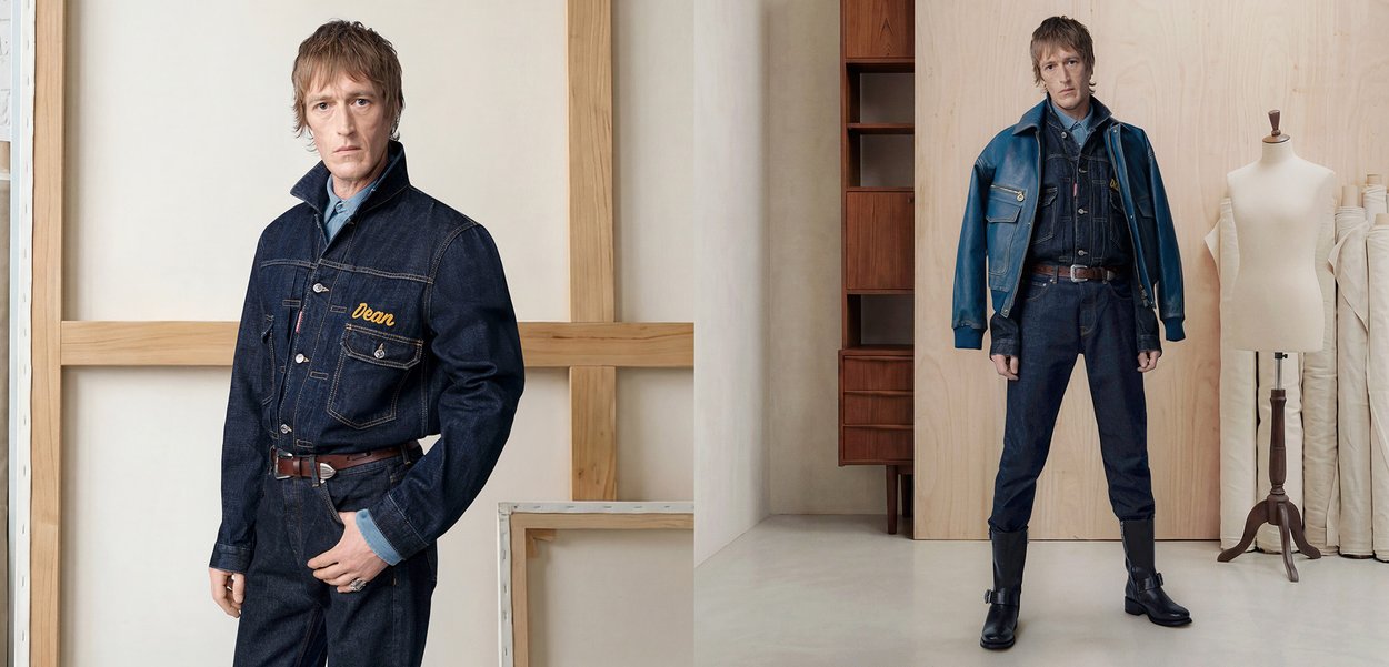 Homme portant une veste en denim foncé et un jean avec une ceinture marron, debout dans une pièce minimaliste avec des meubles en bois et un mannequin de couture.