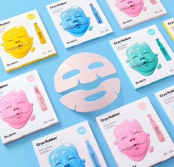 Färgglada Dr.Jart+ Cryo Rubber ansiktsmask-kit i gult, blått, rosa och grönt med en vit pappersmask i mitten på en blå bakgrund.