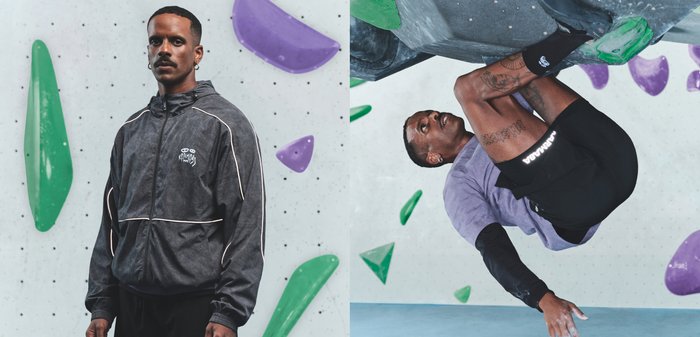 Μαύρο μπουφάν με φερμουάρ και λευκές λεπτομέρειες και λογότυπο, σε συνδυασμό με γκρι μπλουζάκι και μαύρο σορτς, σε έναν τοίχο αναρρίχησης με πολύχρωμες λαβές.