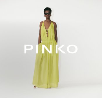Yellow chiffon halter dress with a plunging neckline, cinched waist, and flowing skirt. Model wears round sunglasses and minimalist heels.