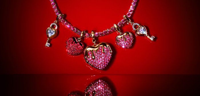 Ketting met roze edelstenen en vijf hangers: twee met goud bedekte harten, twee druppelende roze harten en twee hartsleutelhangers.