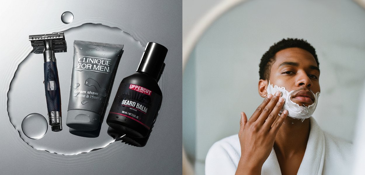 Rasierer mit Holzgriff, graue Rasierschaumtube, schwarze Bartbalsamflasche, alle auf einer reflektierenden Oberfläche mit Wassertropfen.