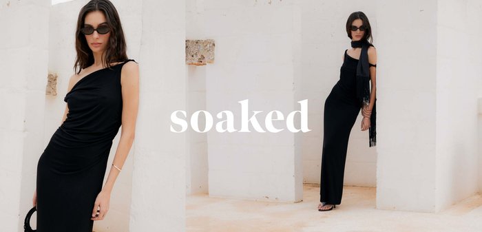 Frau in einem schwarzen ärmellosen Kleid, Schal und Sonnenbrille, die an einer weißen Wand lehnt, mit dem überlagerten Wort „soaked“.