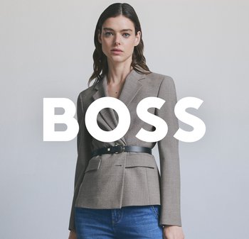 Beige massgeschneiderte Blazerjacke mit Reverskragen, zwei Fronttaschen und einem schwarzen Gürtel, der die Taille betont. Kombiniert mit blauen Jeans.