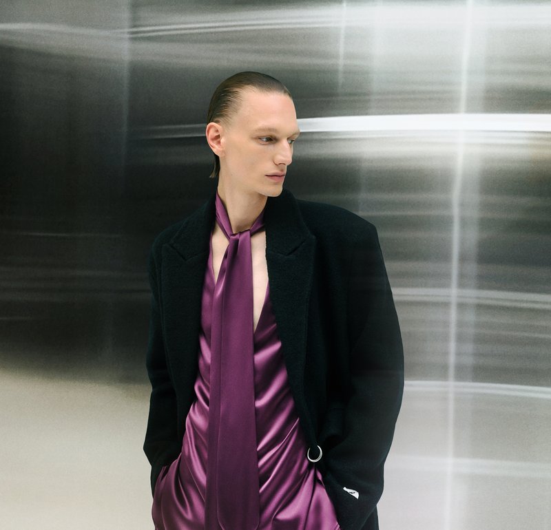 Black coat, deep purple satin shirt with draped texture and matching tie. Smooth background with blurred silver lines.