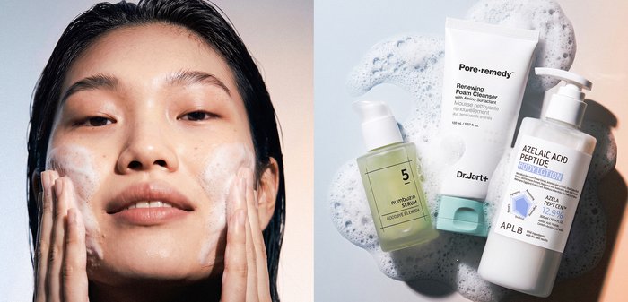 Femme aux cheveux mouillés appliquant délicatement un nettoyant moussant sur ses joues à côté de trois produits de soin de la peau sur une surface recouverte de mousse.