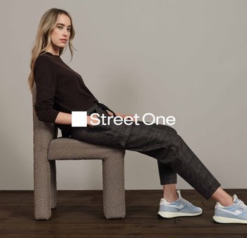 Pull en tricot marron clair, pantalon à motifs gris foncé et baskets bleu clair. La chaise a un revêtement texturé beige et un design simple.