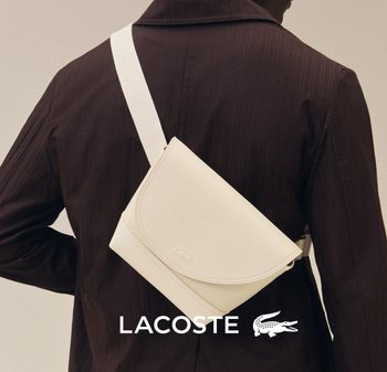 Persona con una chaqueta marrón oscuro y un bolso blanco cruzado colgado del hombro sobre un fondo liso.