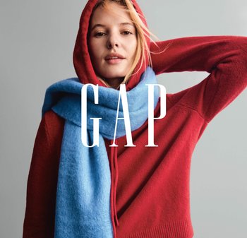 Rød sweater med hætte, lagdelt under et lyseblåt, blødt tørklæde. Modellen har løst hår, med en neutral baggrund og fed "GAP"-tekst.