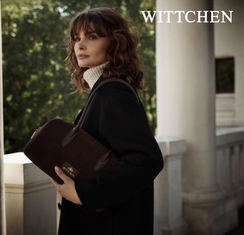 Brązowa torebka z zamszu z skórzanymi akcentami, zamknięcie na zamek i złote logo z przodu. Posiada podwójne uchwyty i usztywniony kształt.