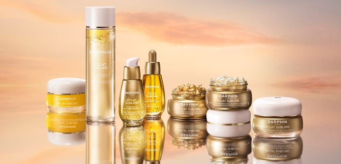 Huit produits de soin de la peau de Darphin, présentant des contenants jaunes et dorés avec différentes formes et textures, étiquetés « Éclat Sublime ».