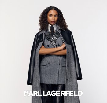 Chaqueta de traje gris de lana de doble botonadura con un abrigo de cuero negro y un chaleco estampado. Camisa blanca con cuello, corbata negra y pantalones negros brillantes.