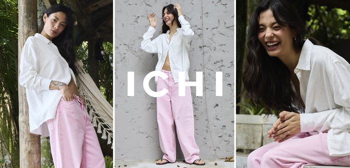 Jeune femme en chemise blanche et pantalon rose, appuyée contre un poteau en bois près d'un hamac sous un abri tropical en plein air.