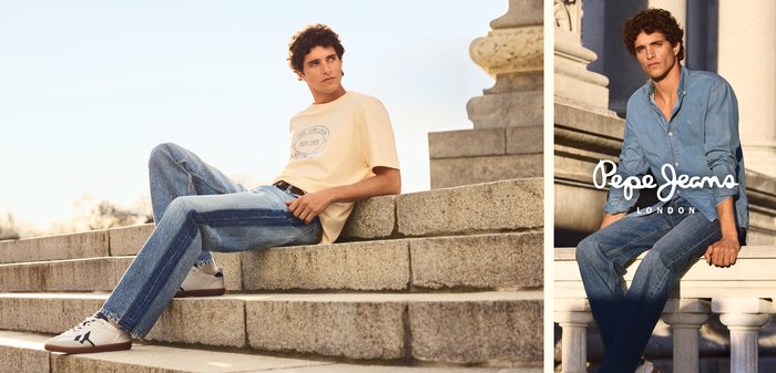 Giovane uomo con capelli ricci che indossa jeans casual e una t-shirt, seduto su gradini di pietra all'aperto alla luce del giorno.
