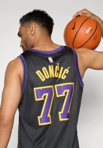 Must korvpallivorm seljal, millel lillad aktsendid, taga säravad kollased tähed "DONČIĆ" ja number "77". Mängija hoiab korvpalli.