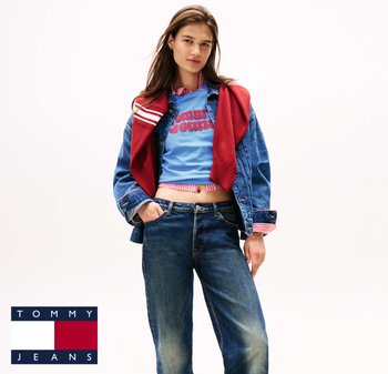 Denim jacket over a light blue cropped t-shirt with red text, paired with mid-rise blue jeans and a red sweater draped around the shoulders.