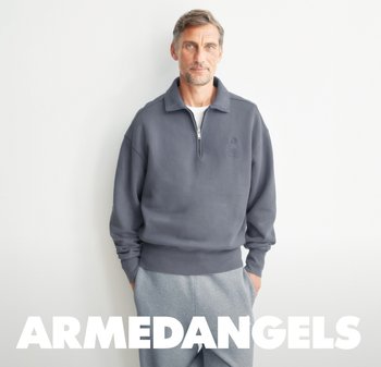Gray zip-up sweatshirt with ribbed cuffs and hem, featuring a subtle logo on the chest, paired with light gray sweatpants.