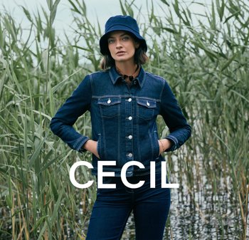 Donkerblauwe denimjack met twee borstzakken, zilveren knopen en een gestructureerde kraag, gecombineerd met donkere jeans en een blauwe bucket hat.
