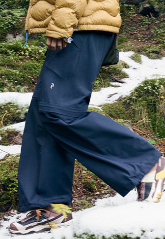 Ναυτικό μπλε παντελόνια σε ευρεία γραμμή από ελαφρύ ύφασμα, με πλαϊνές τσέπες και ένα μικρό έμβλημα. Συνδυασμένα με μοτίβα αθλητικά παπούτσια σε χιονισμένο φόντο.