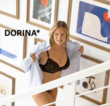Soutien-gorge en dentelle noire avec bretelles réglables, associé à une culotte en dentelle noire, complété par une chemise à boutons bleu clair. Escalier blanc et œuvres d'art en arrière-plan.