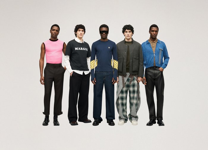 Fem män står sida vid sida och bär olika moderna outfits, inklusive ett rosa ärmlöst linne, en grafisk sweatshirt, marinblå långärmad tröja, en quiltad jacka och en blå jacka med dragkedja.