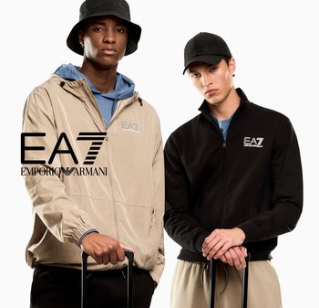 Dwóch mężczyzn nosi kurtki i czapki EA7 Emporio Armani, każdy trzymając za uchwyt walizki na białym tle.