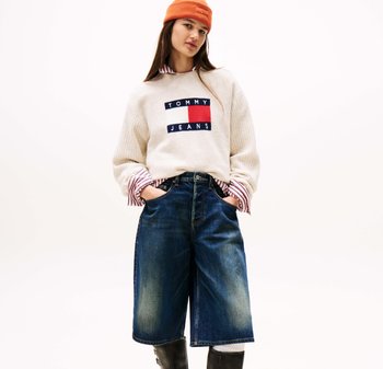 Cream sweater with "TOMMY JEANS" logo, blue denim culottes, and an orange beanie. The sweater has ribbed texture; culottes are loose-fitting.