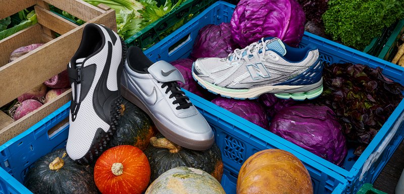 Deux paires de chaussures de sport sur des légumes colorés : une paire noir et blanc avec une tige texturée et une paire argentée avec des accents et des lacets noirs.