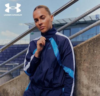 Chándal deportivo azul marino con acentos en azul claro y blanco, con cuello alto y puños elásticos. Logo de Under Armour visible.